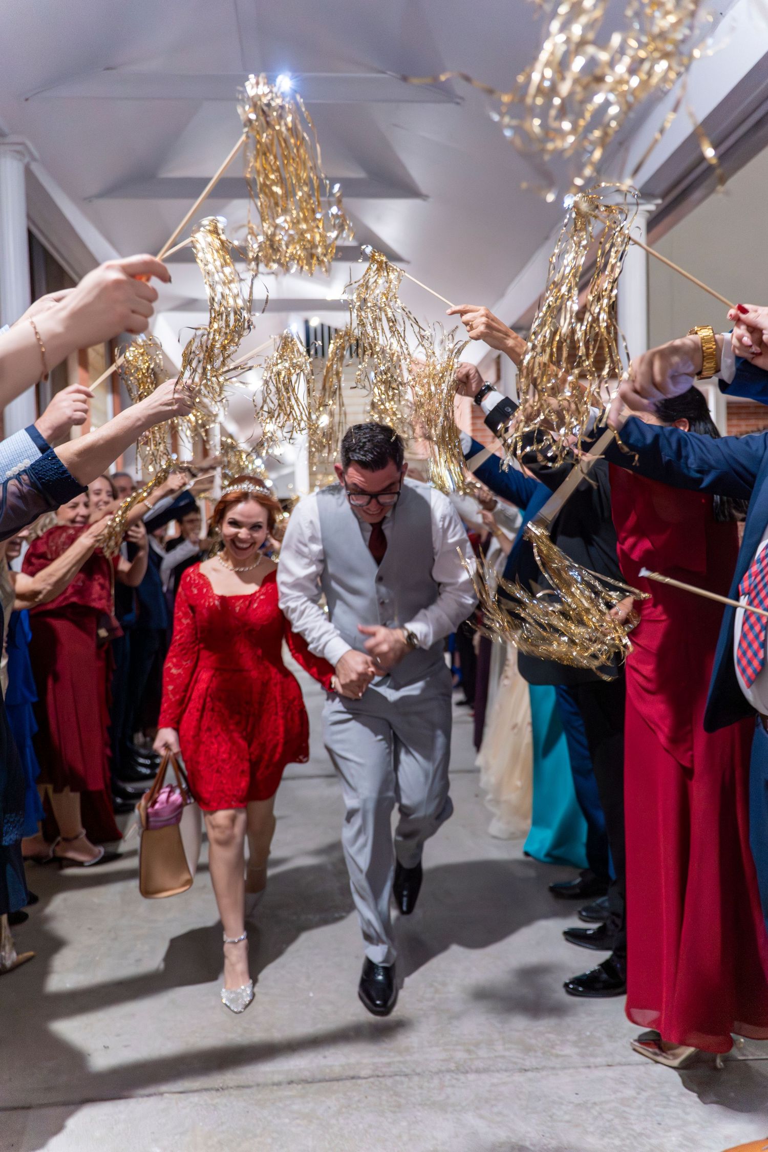Wedding guests create a festive tunnel with sparklers as people walk underneath at an evening celebration.