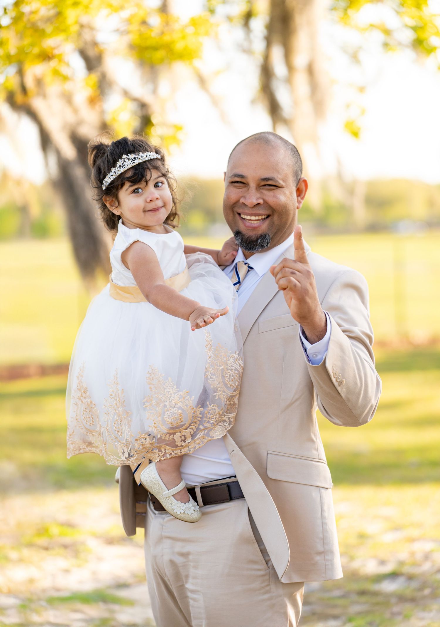 A tender outdoor family moment captured in warm sunlight among autumn trees.