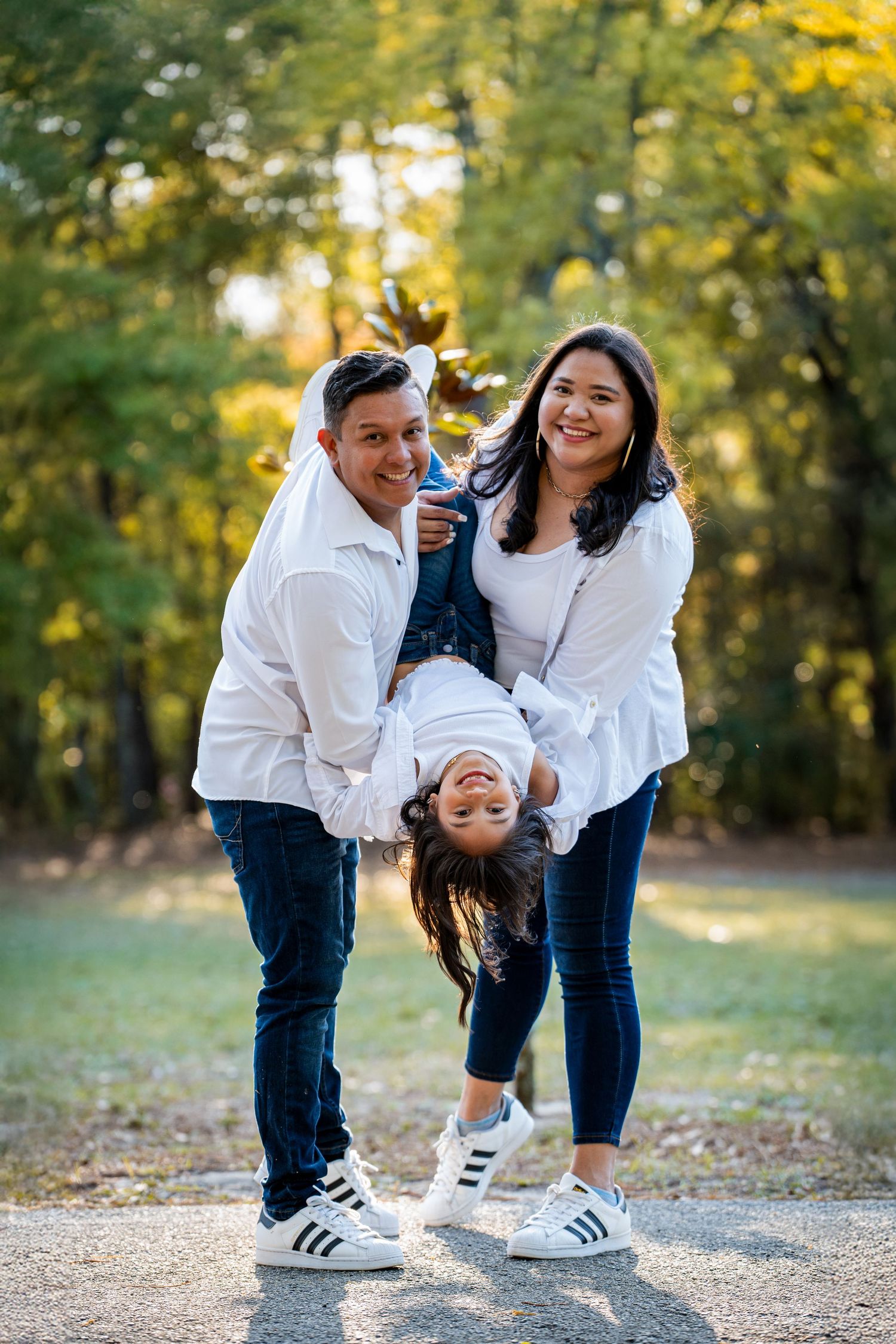 A joyful family moment captured outdoors with yellow fall foliage in the background.
