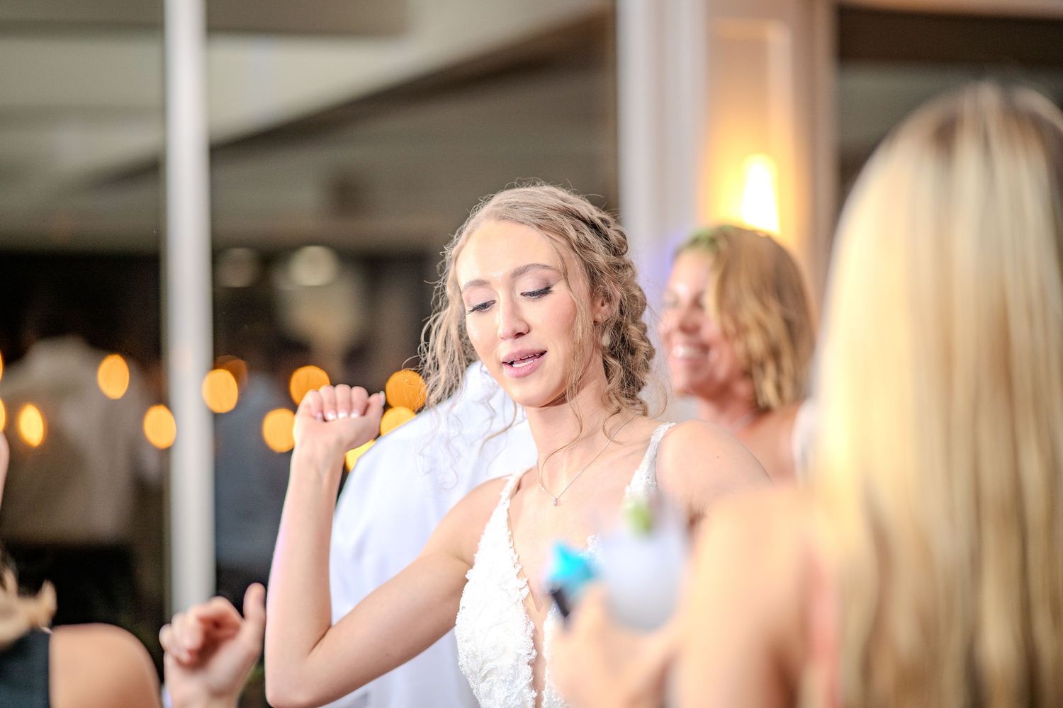 People dancing and celebrating at a festive event with soft lighting and party decorations in the background.