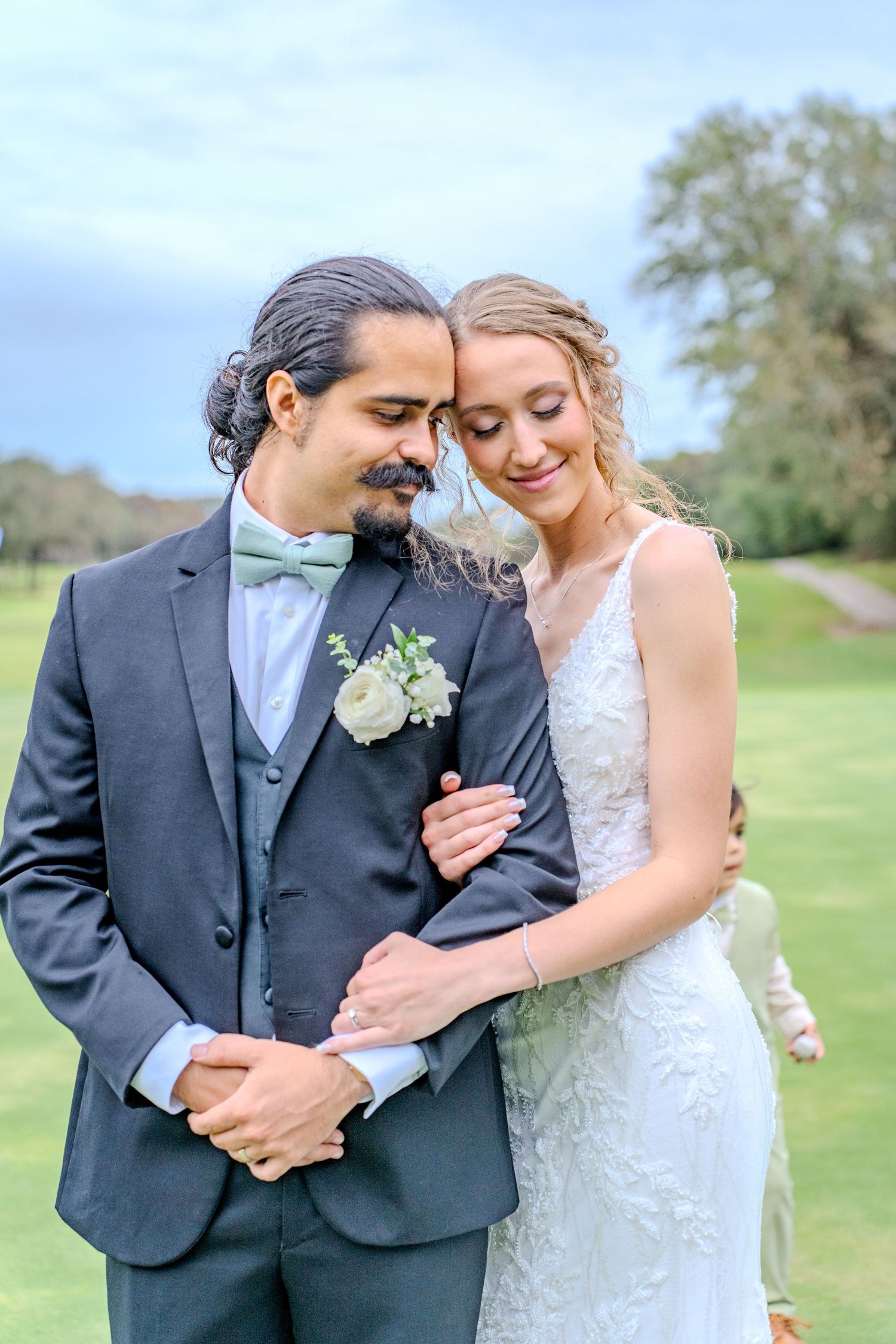 Romantic outdoor wedding portraits show couple embracing in lush garden setting wearing formal attire.