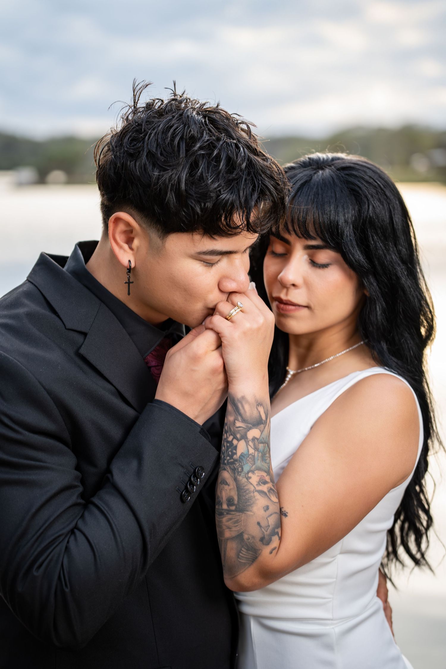 A romantic couple shares tender intimate moments in black and white photography at outdoor location.