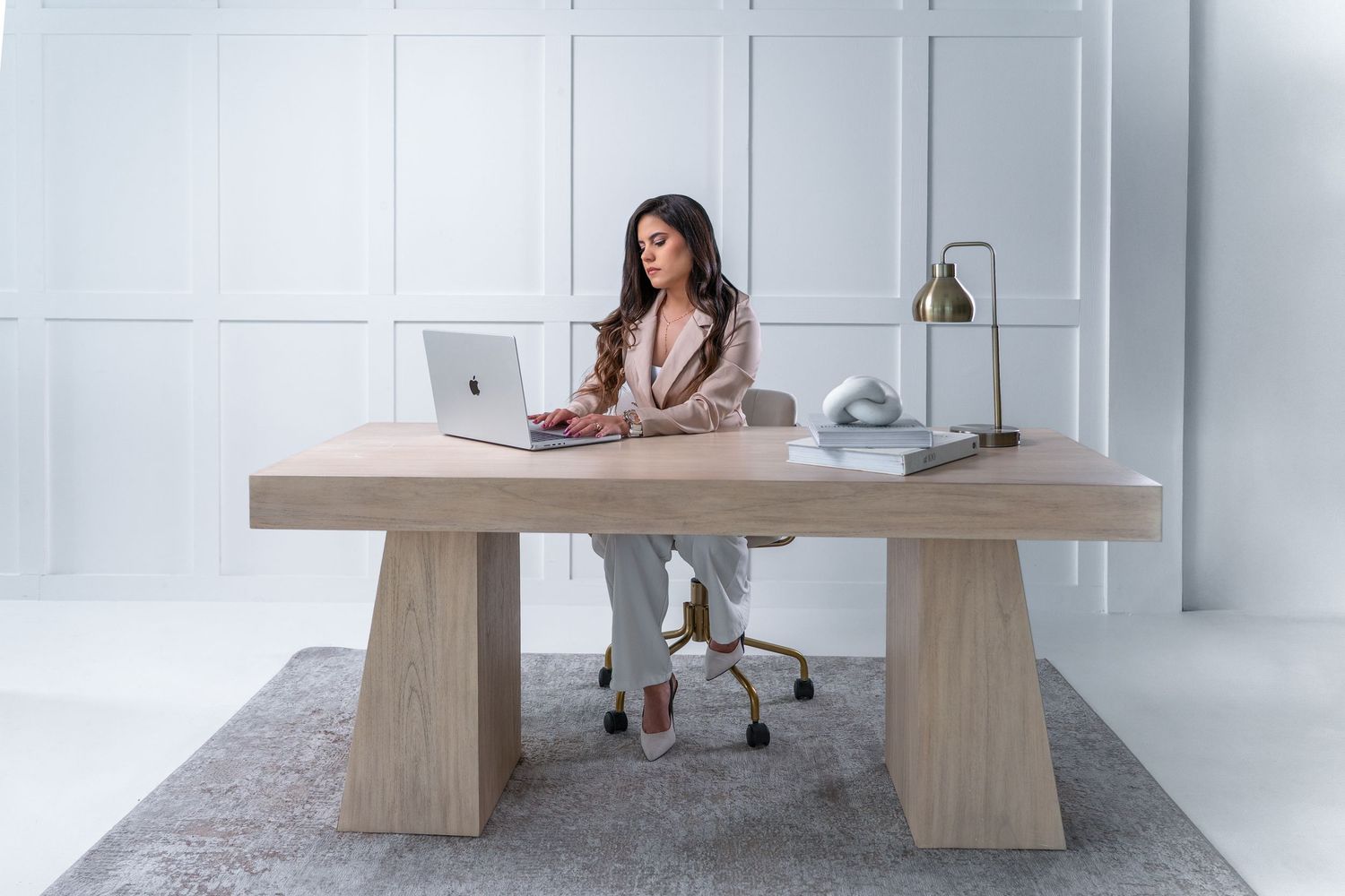 Modern dining room interior with light wood table and benches against white walls and grey carpet.