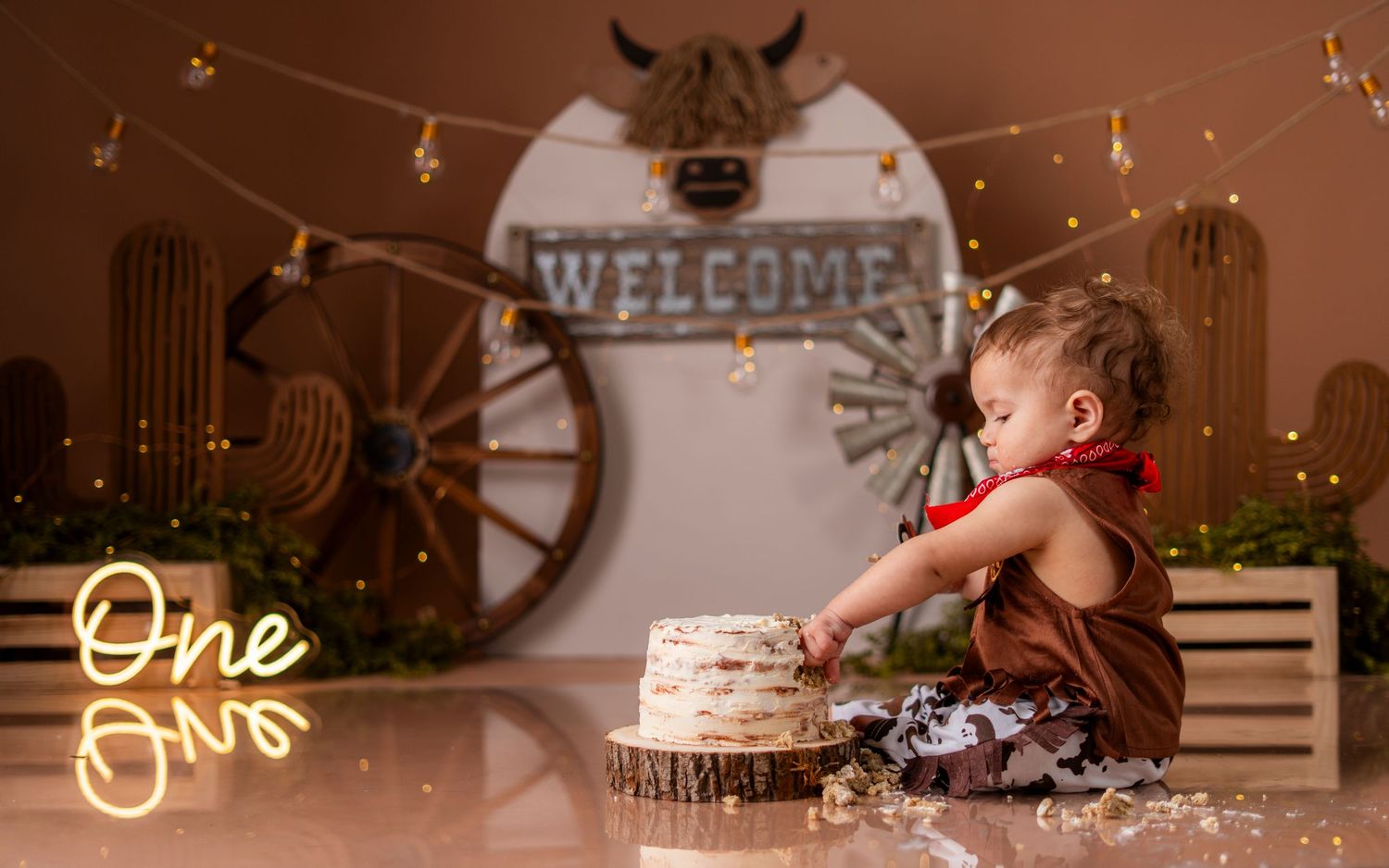 A person sits on a wooden floor near twinkling string lights and rustic decor in a cozy indoor setting.