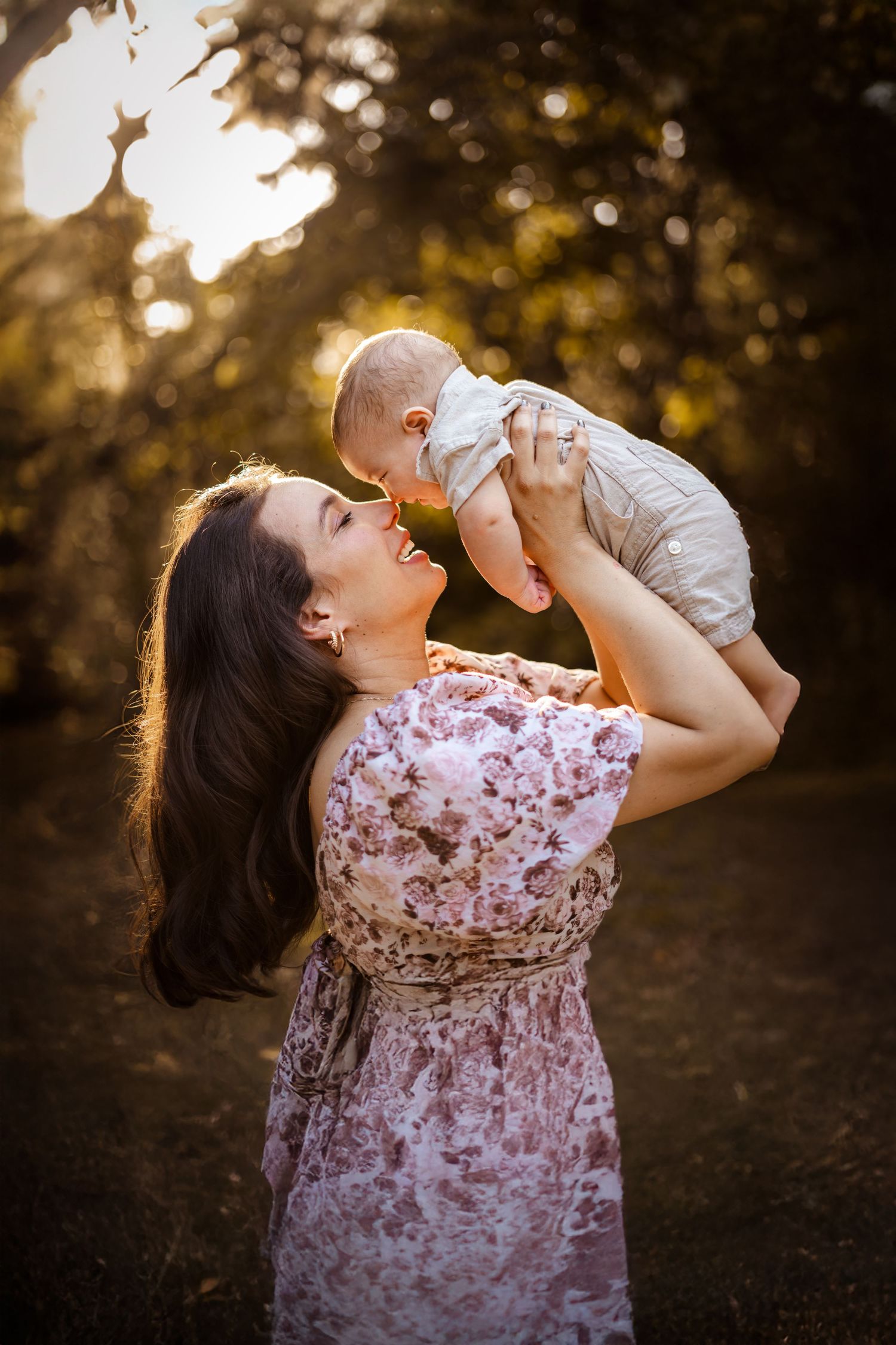 Person in floral dress tilts head back while drinking from bottle at golden sunset against dark background.