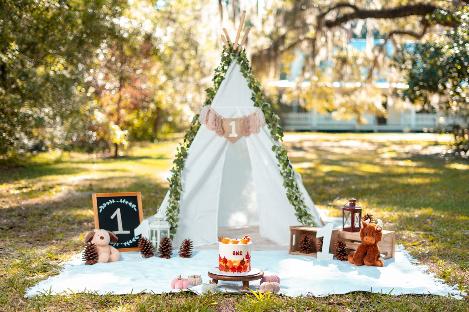 A romantic outdoor picnic setup with white blankets, vintage furniture, and fall foliage in a sunlit garden setting.