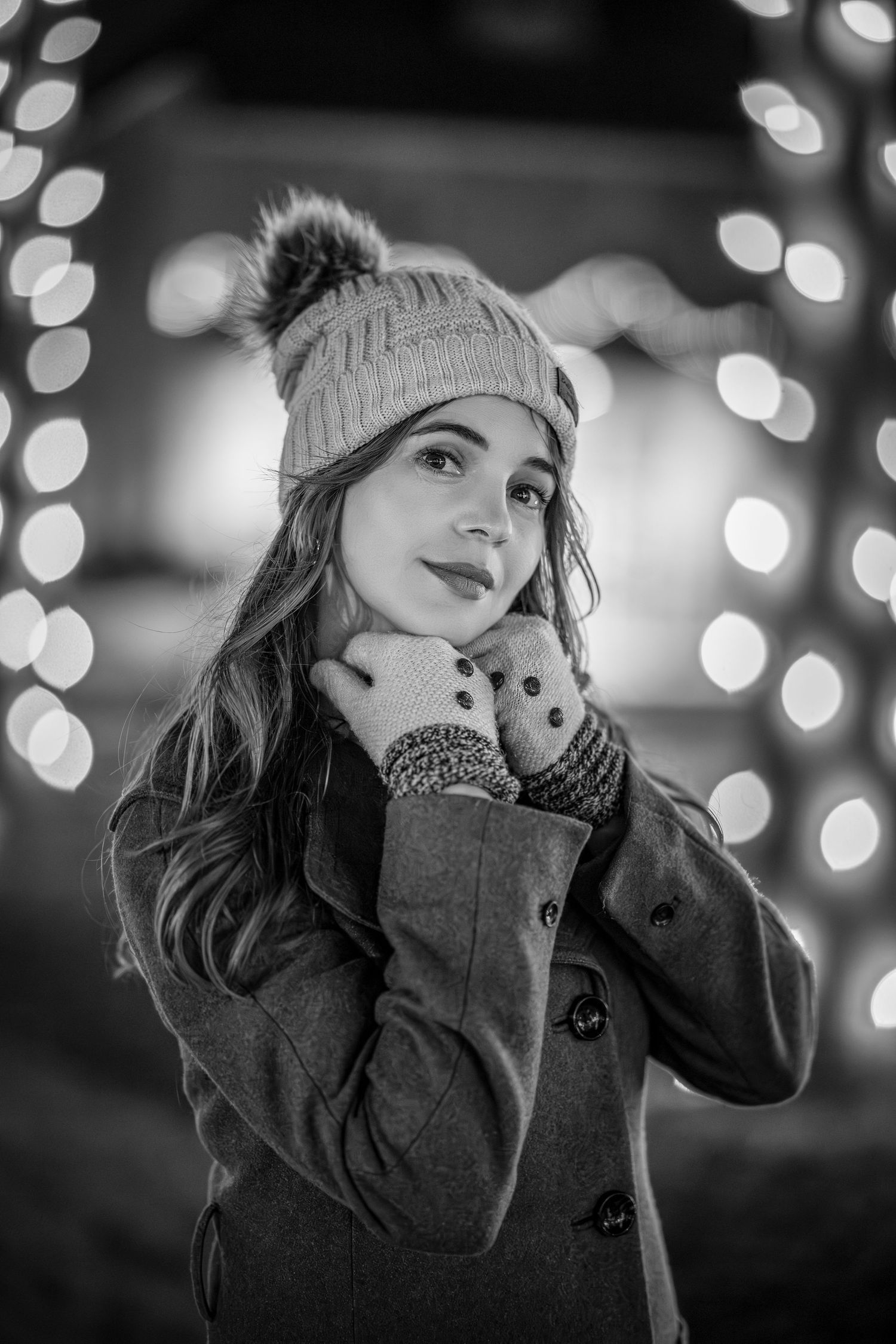 Black and white portrait series with bokeh lights showing contemplative expressions against blurred holiday lighting.