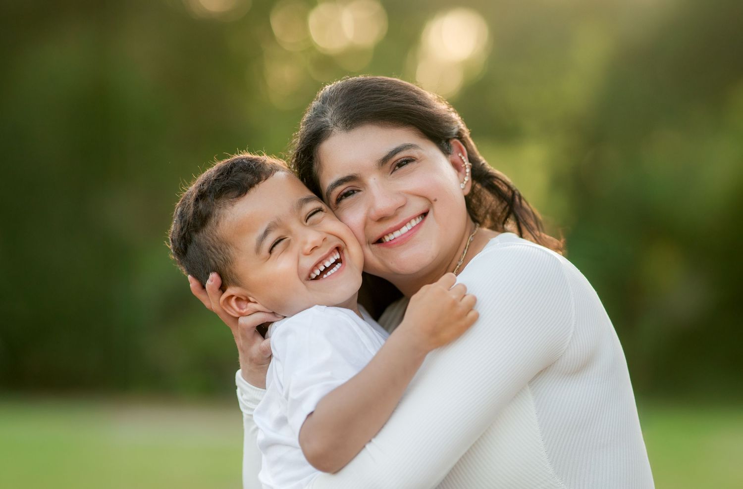 A loving embrace between parent and child is shared in a bright outdoor garden setting.