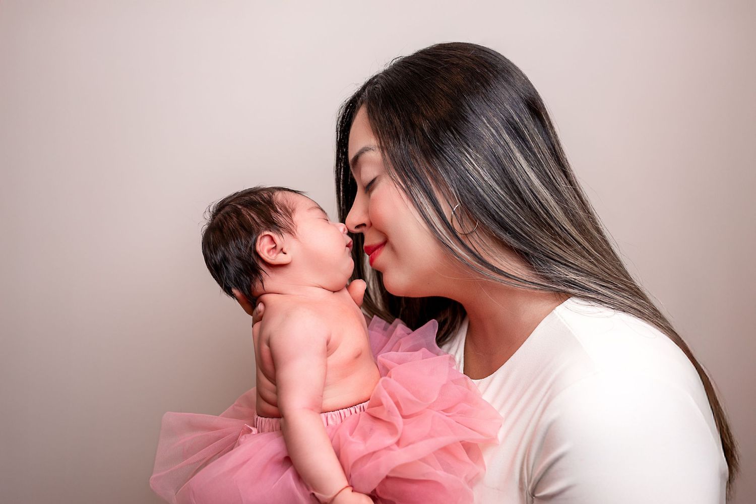 A tender loving moment between parent and child in soft pink hues against a neutral background.