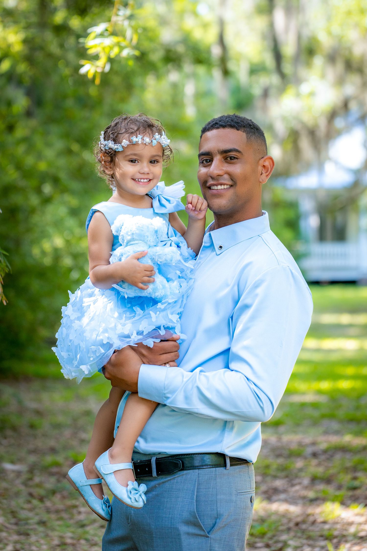 Two people wearing matching light blue outfits share joyful moments in a sunny outdoor garden setting.