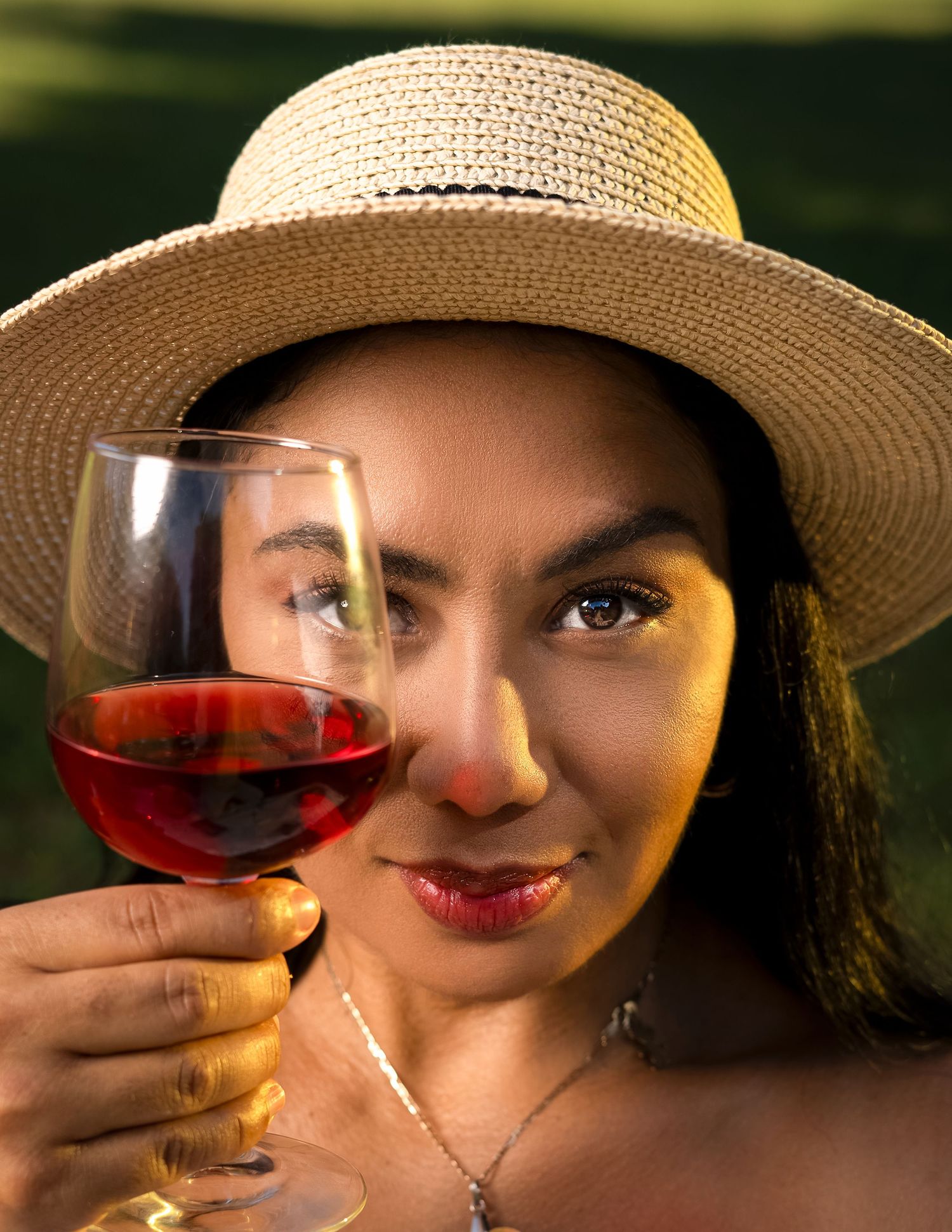 Artistic photo series showing someone in a straw hat holding up a glass of red wine in warm lighting.
