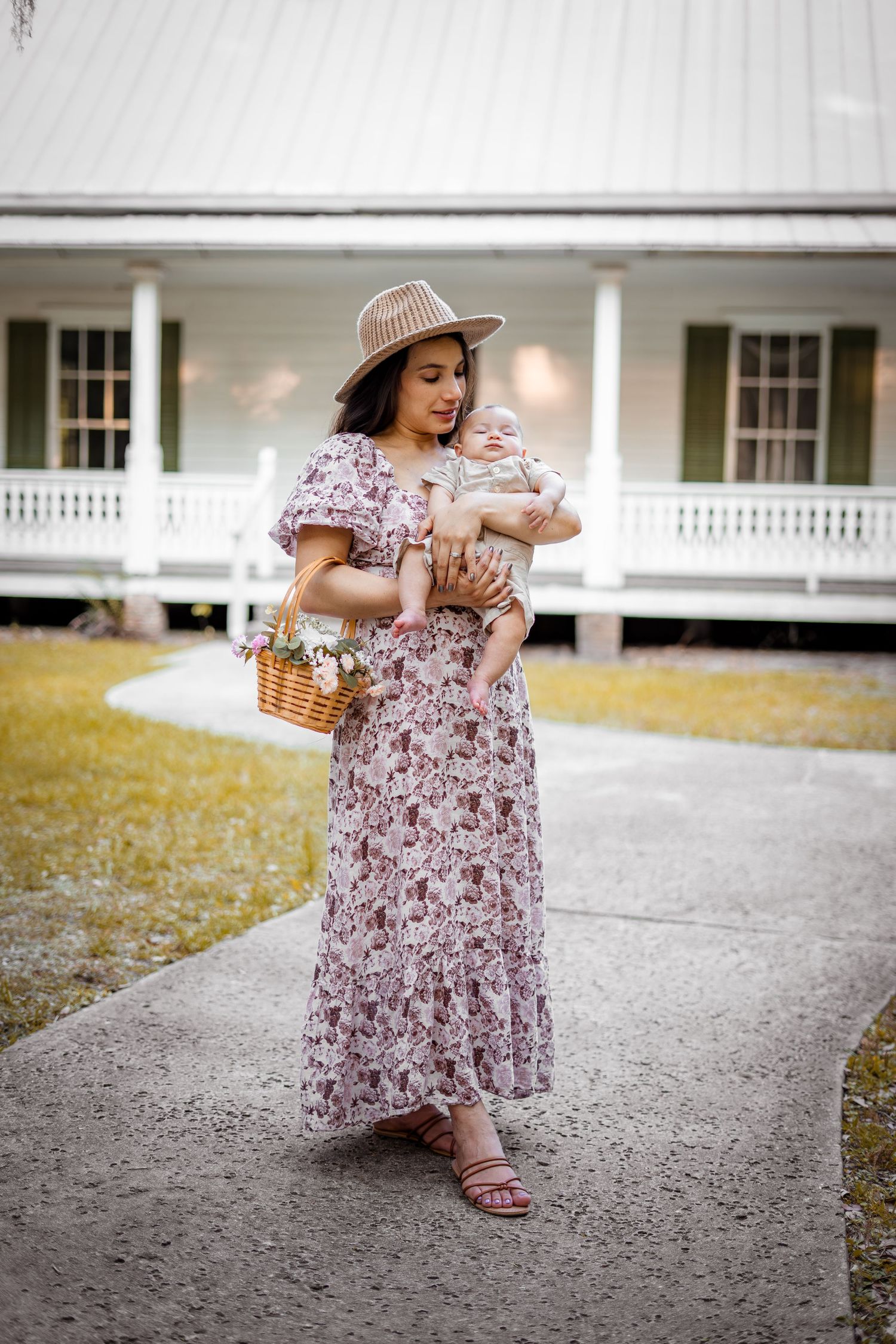 A person in a floral dress spins gracefully outdoors near a white pillared building on a sunny day.