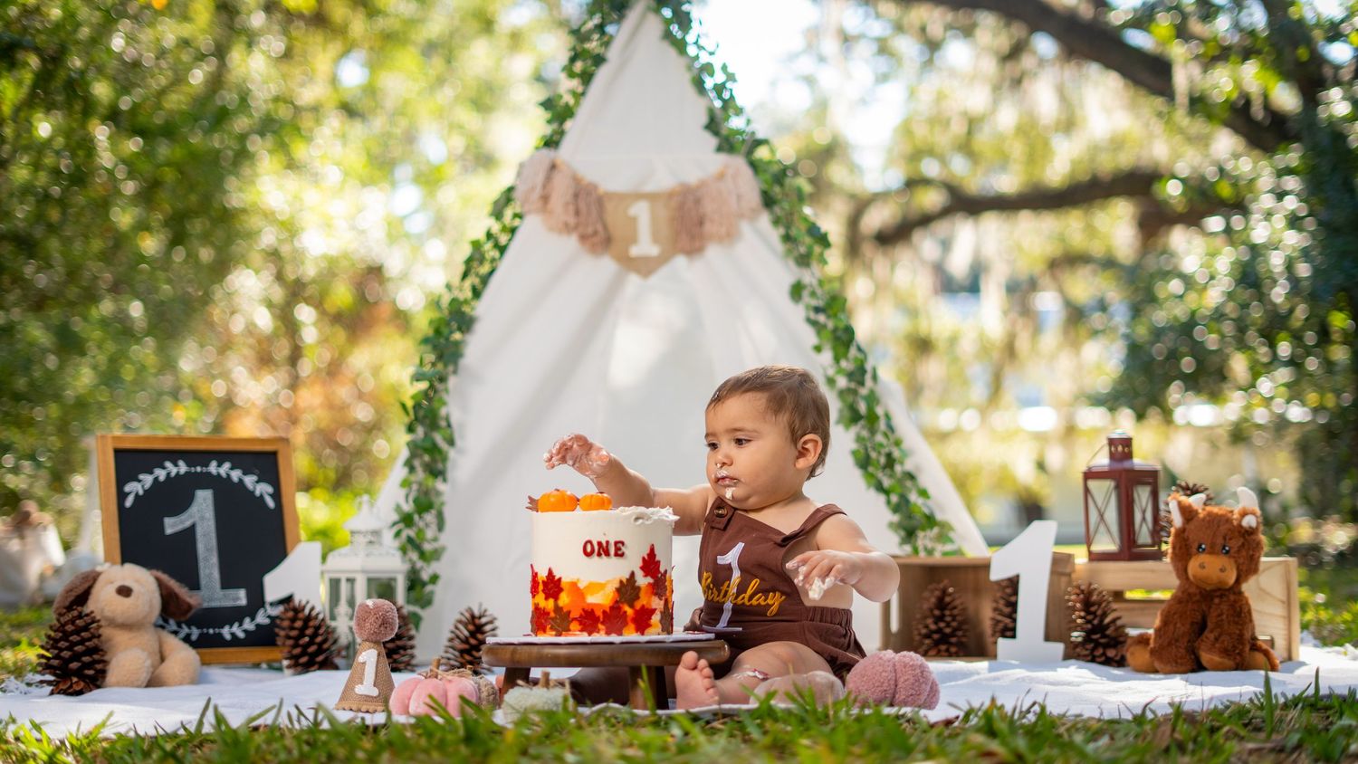 Outdoor party setup with rustic wooden decorations and string lights hanging from trees.