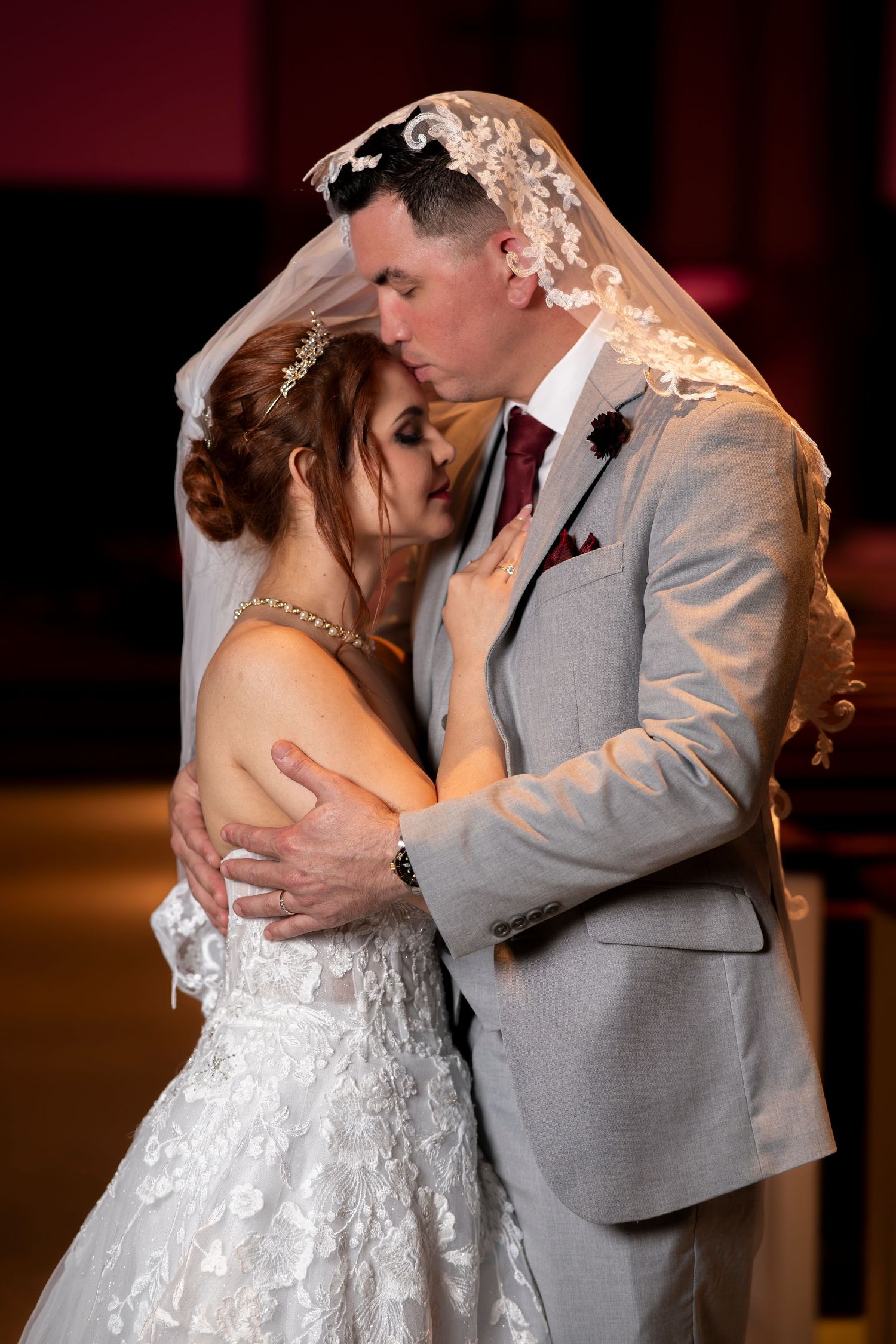Newlywed couple shares romantic kisses in sequence wearing gray suit and white lace wedding dress.