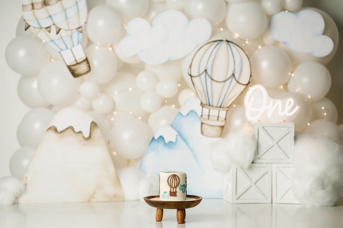 A whimsical nursery wall decorated with white clouds, hot air balloons, and soft lighting creates a dreamy atmosphere.