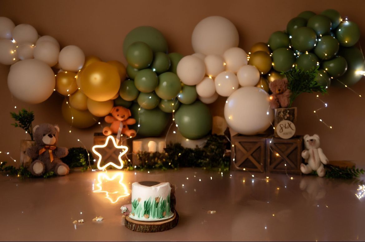 Festive party setup with green and white balloon garlands, twinkling lights, and a glowing star decoration.