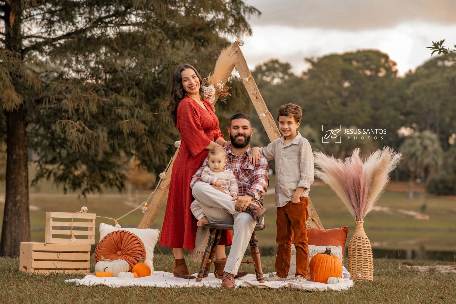 Family enjoying autumn picnic in park with pumpkins and blankets at sunset.