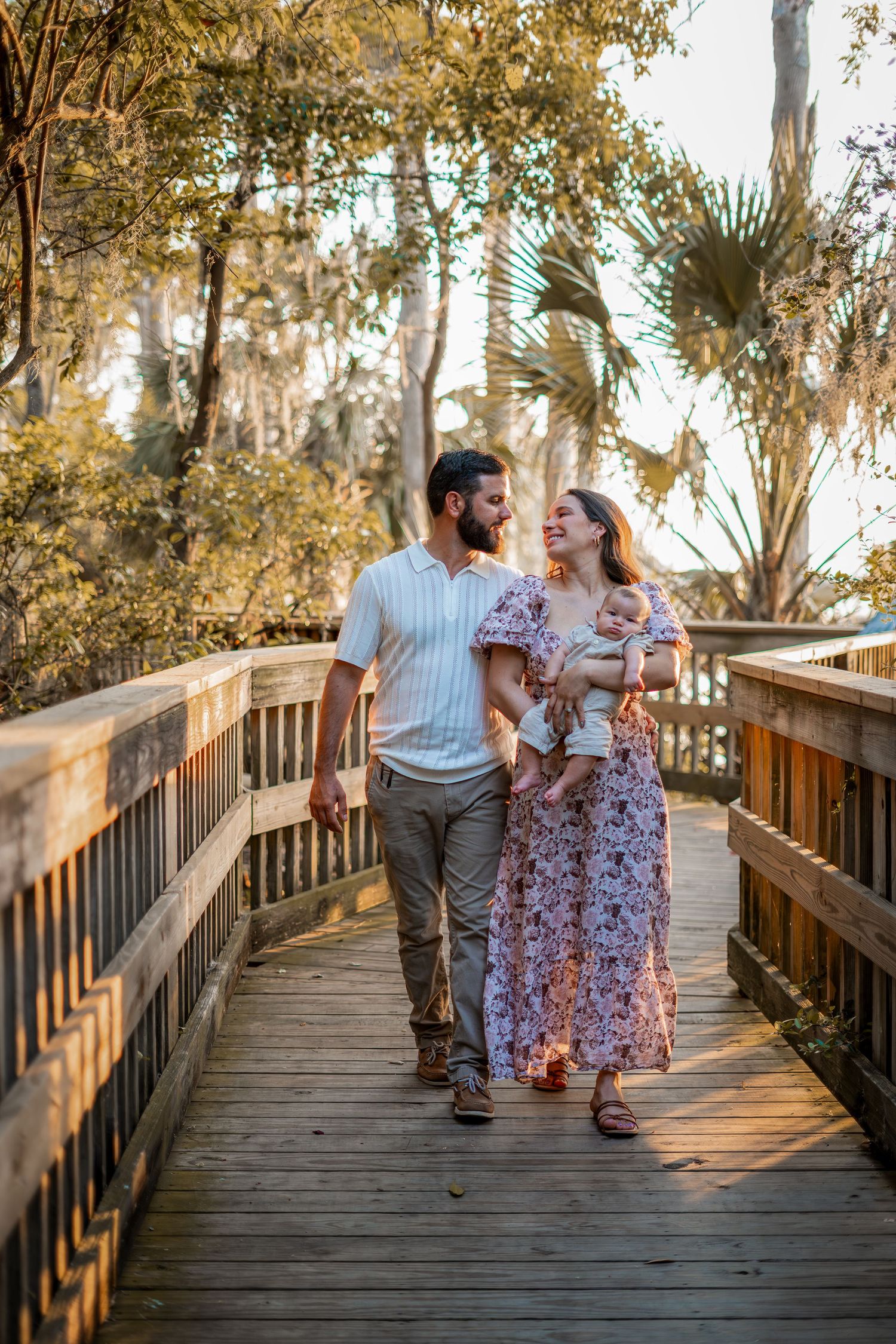 A couple shares a tender moment while walking together on a wooden boardwalk during golden hour.