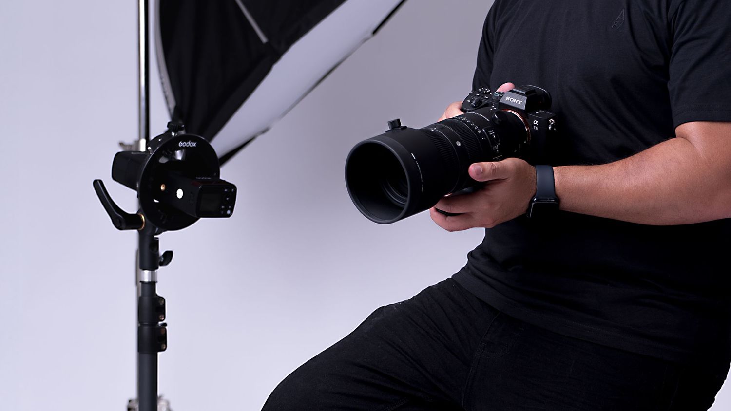 Person wearing black gloves holds a camera flash diffuser attachment in detailed product demonstration sequence.