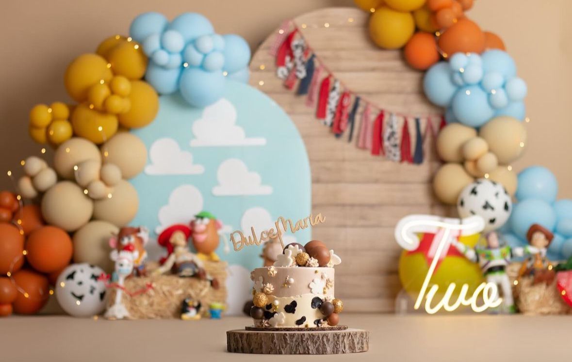 Colorful balloon garland with pastel blue, orange, and yellow balloons decorates a wooden backdrop for party decor.