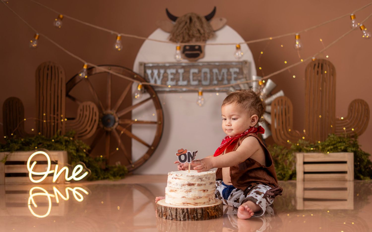 A baby in a festive holiday setting crawls on the floor near twinkling lights and rustic Christmas decorations.