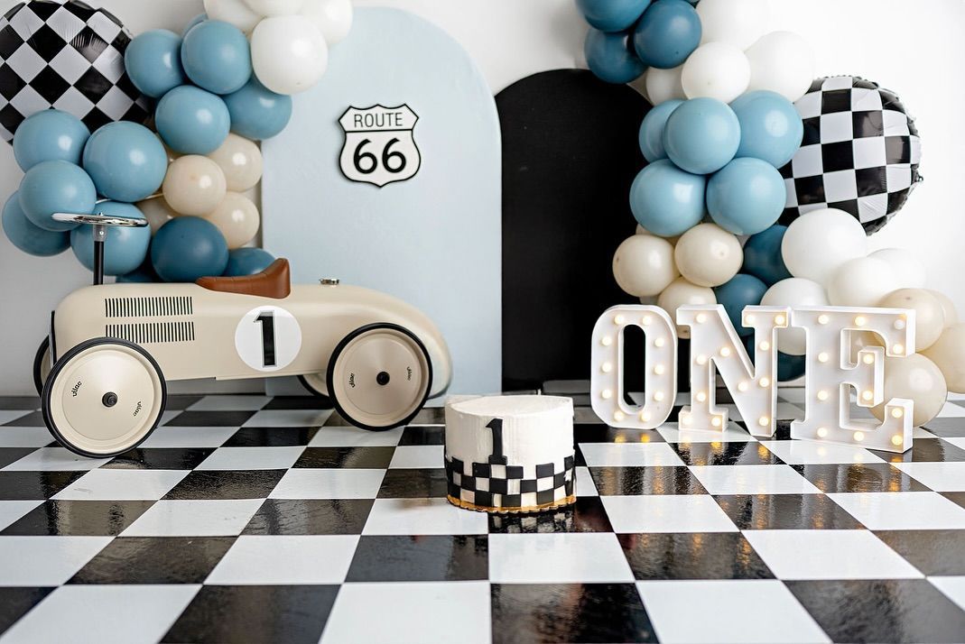 Blue and white balloon arch with checkered pattern and Route 66 sign against white background.