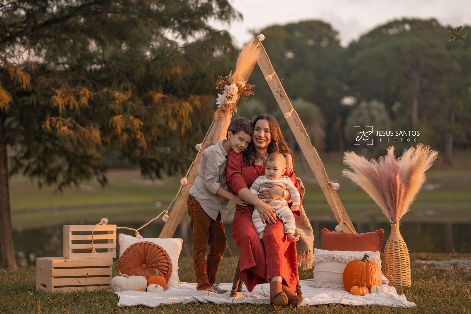 Fall family photoshoot with pumpkins and wooden crates in a rustic outdoor setting during golden hour.