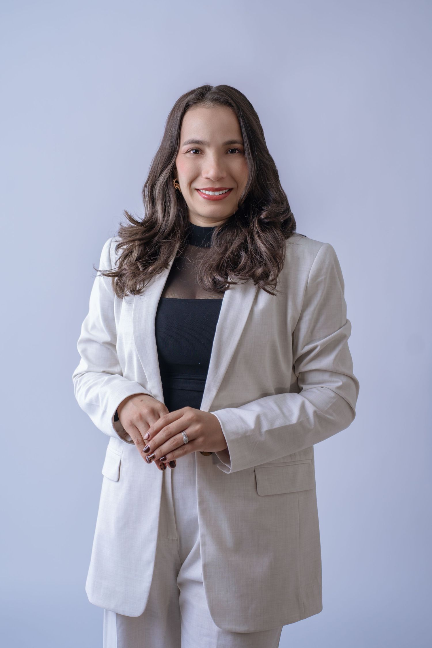 Professional wearing a white blazer and black top poses against light background in a series of business headshots.