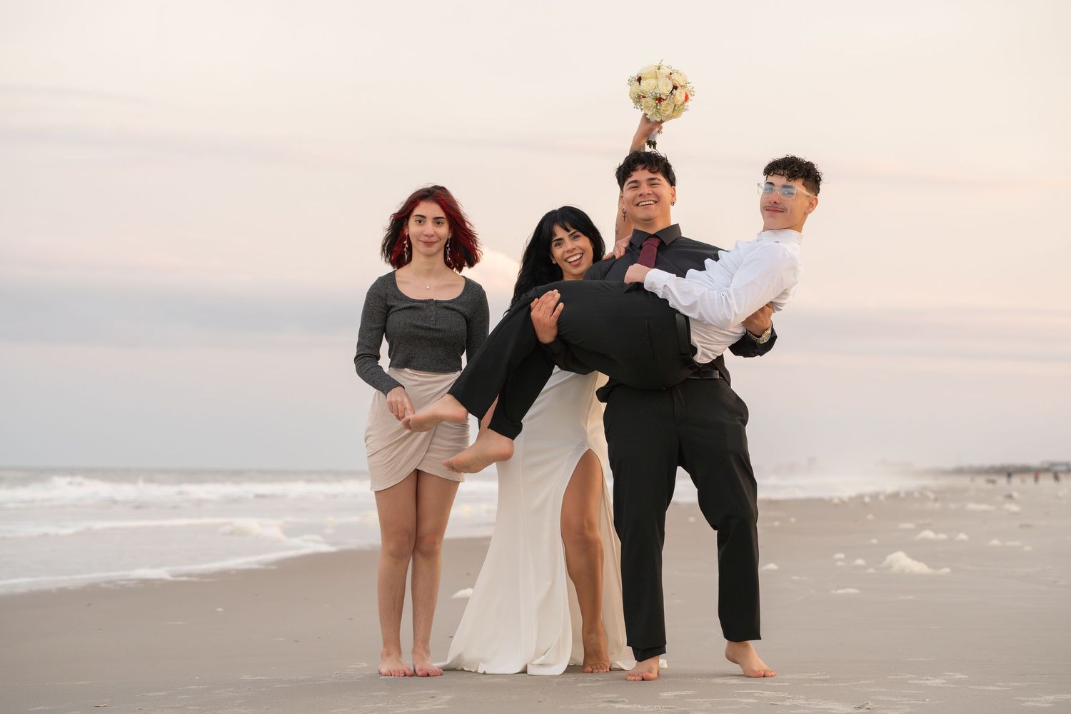 A joyful group walks together along a scenic beach at sunset in casual attire.