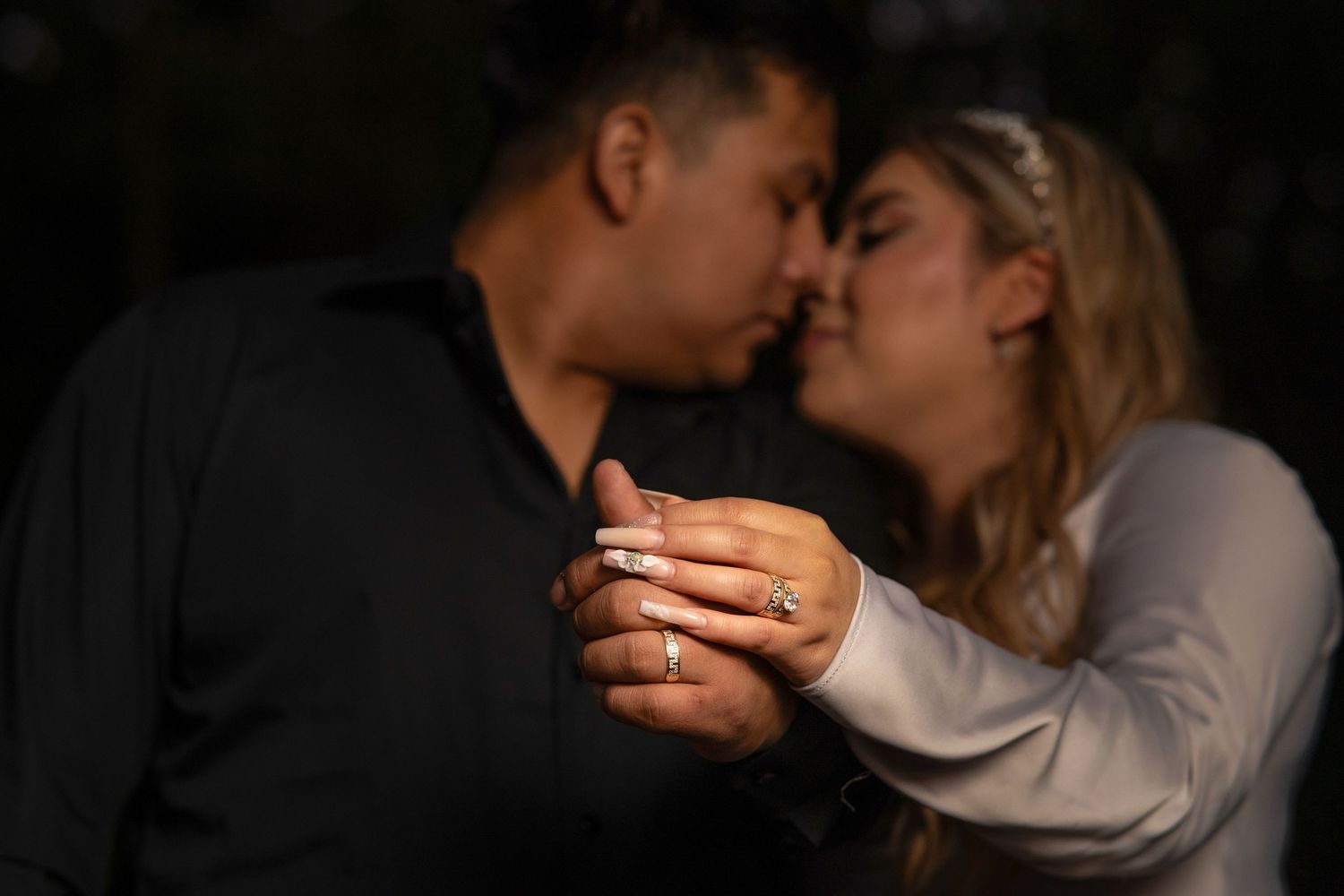A romantic couple shares an intimate moment while holding hands in dim lighting.