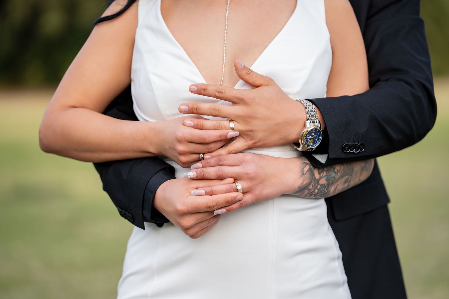 A close-up of wedding rings being exchanged between a bride and groom during an outdoor ceremony.