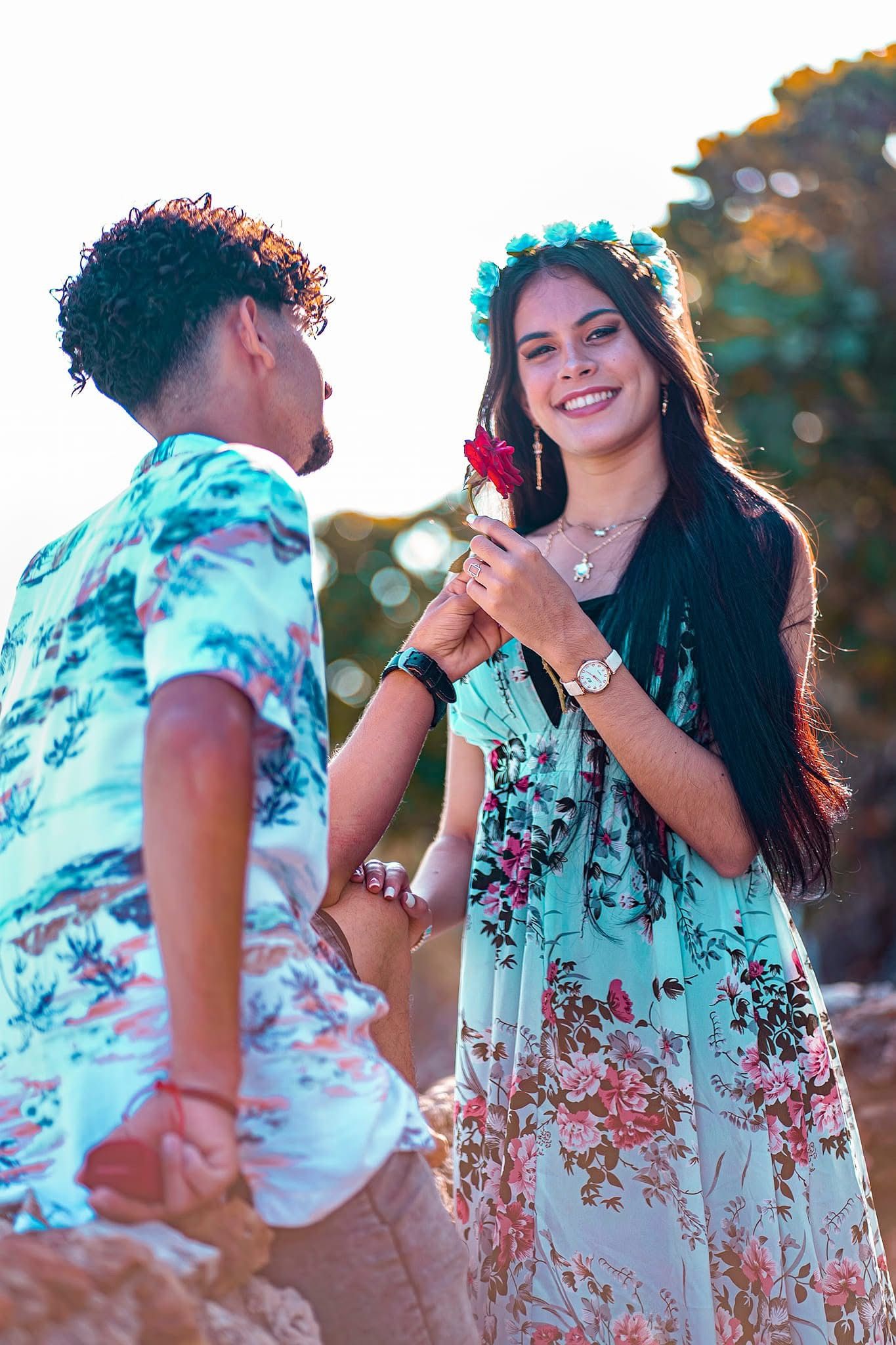 A couple in matching mint floral outfits embrace during a romantic outdoor photoshoot at sunset.