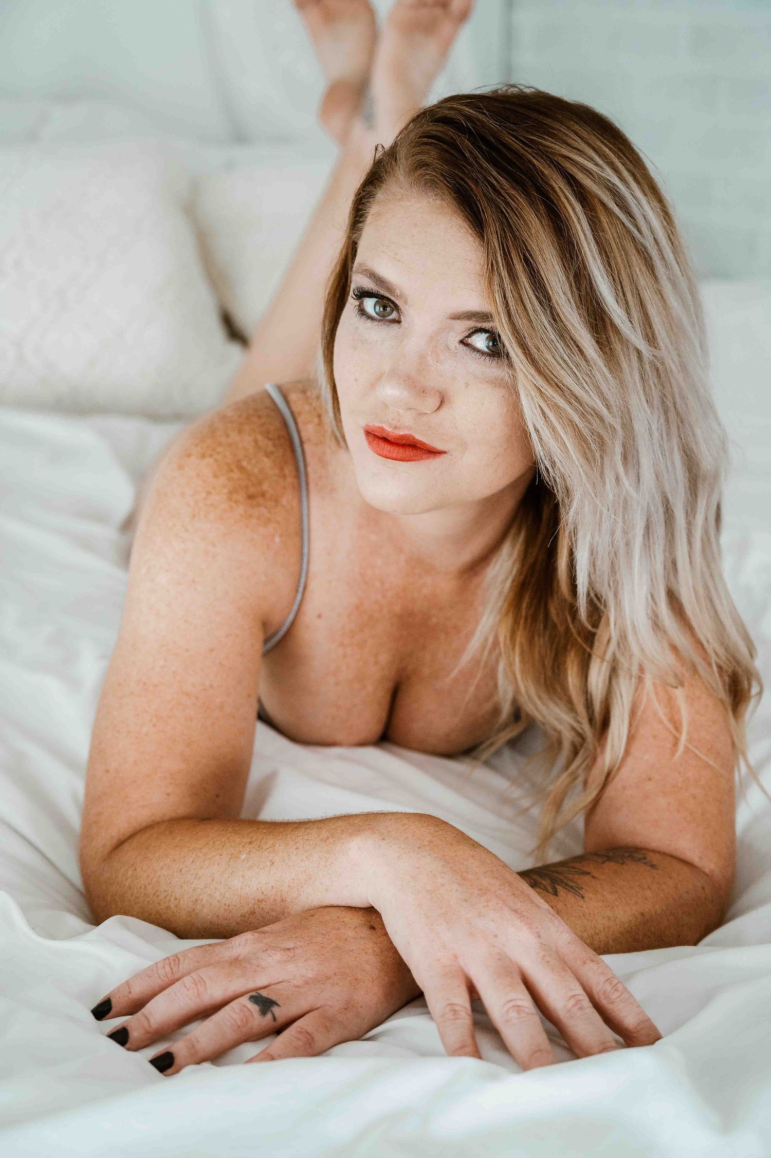 Blonde woman with red lipstick laying on bed smiling