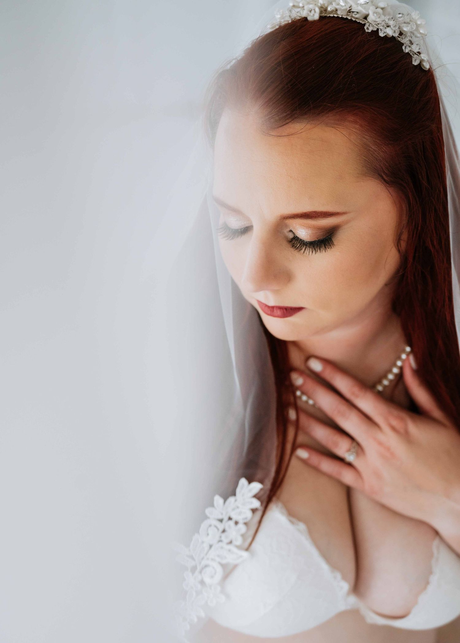Bridal boudoir photography – elegant bride in veil and pearls, intimate and graceful.