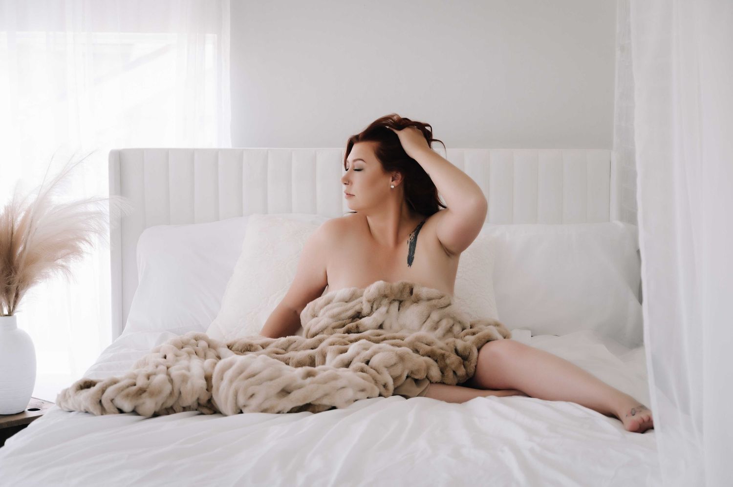Boudoir photography – woman draped in fur blanket, serene and confident.