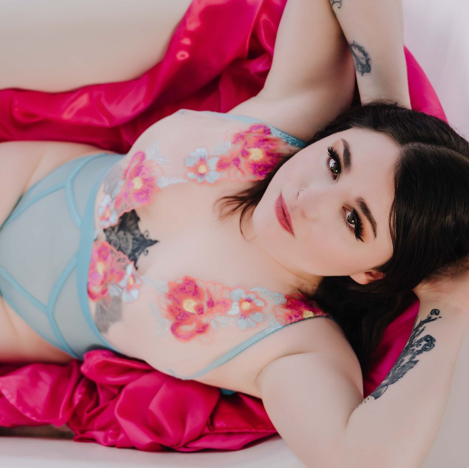 Boudoir portrait – woman in floral lingerie on pink satin, bold and beautiful.