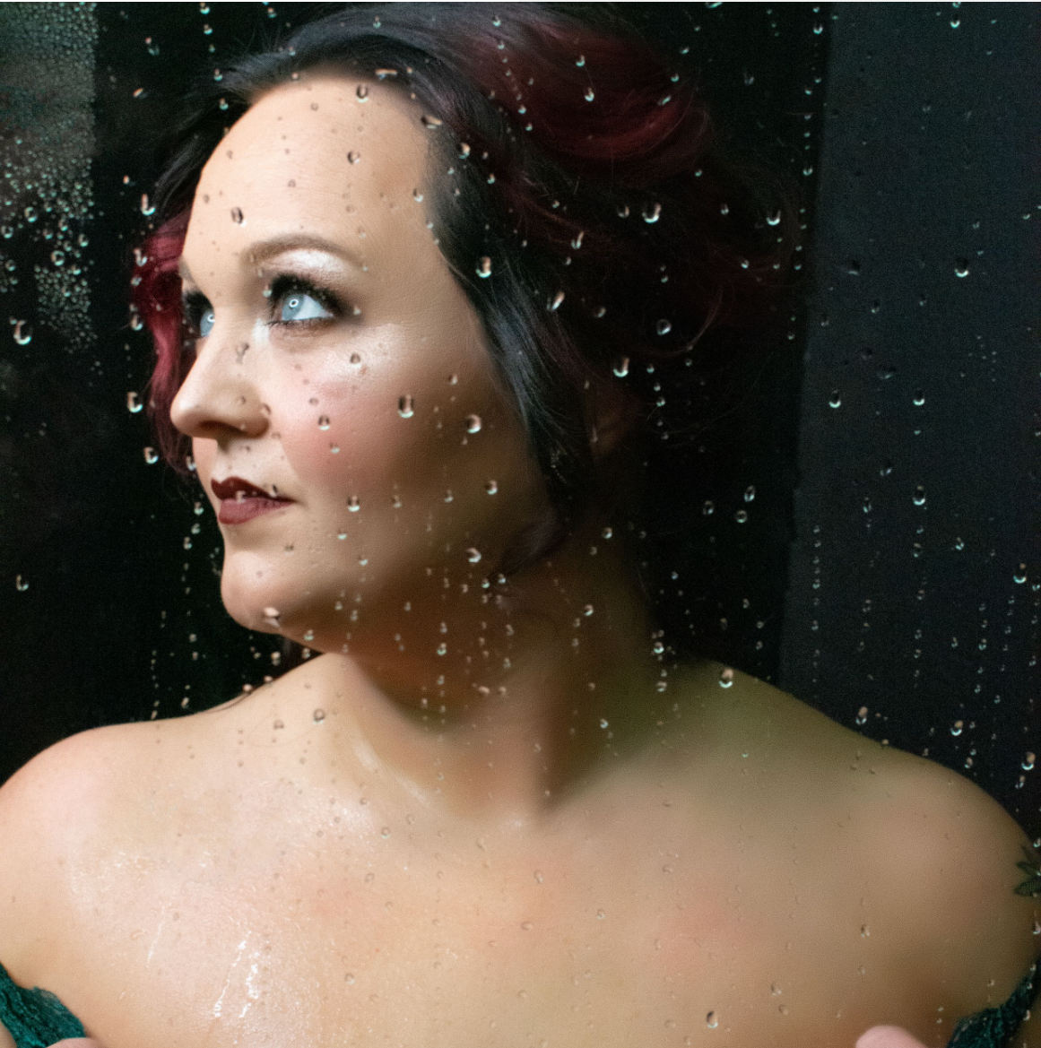 blue eyed woman behind wet glass of shower