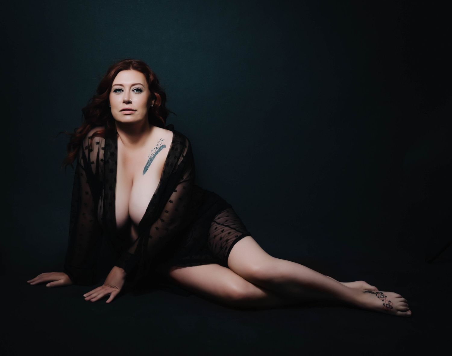 Moody boudoir photography – woman in sheer black robe on dark backdrop, powerful and elegant.