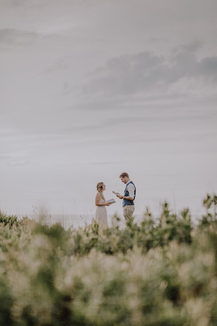 Couple elopement portraits on a cliffside at sunset. They are exchanging vows amongst the wild greenery on the  cliff, o