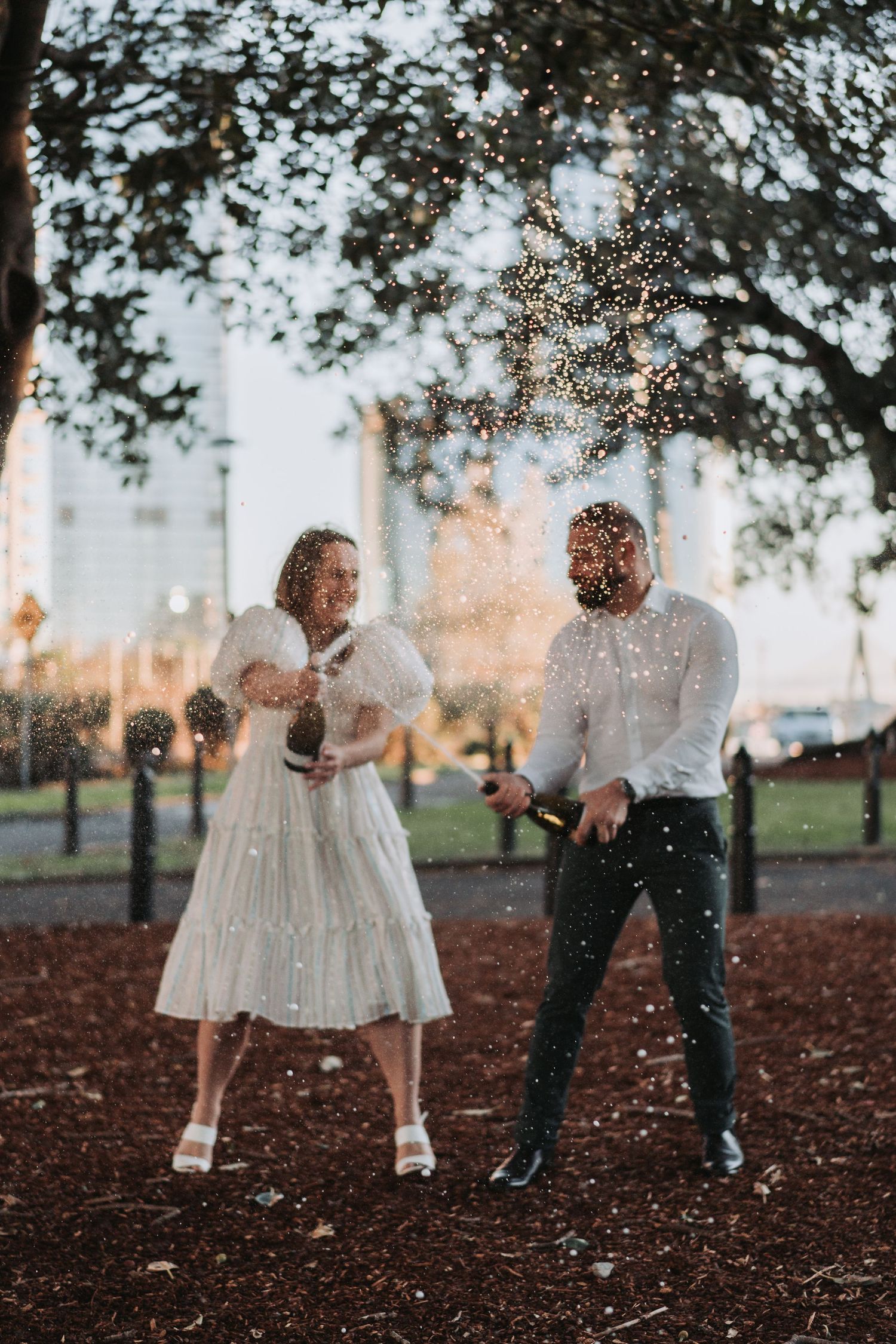 A romantic outdoor scene with sparklers and twinkling lights under trees at dusk.