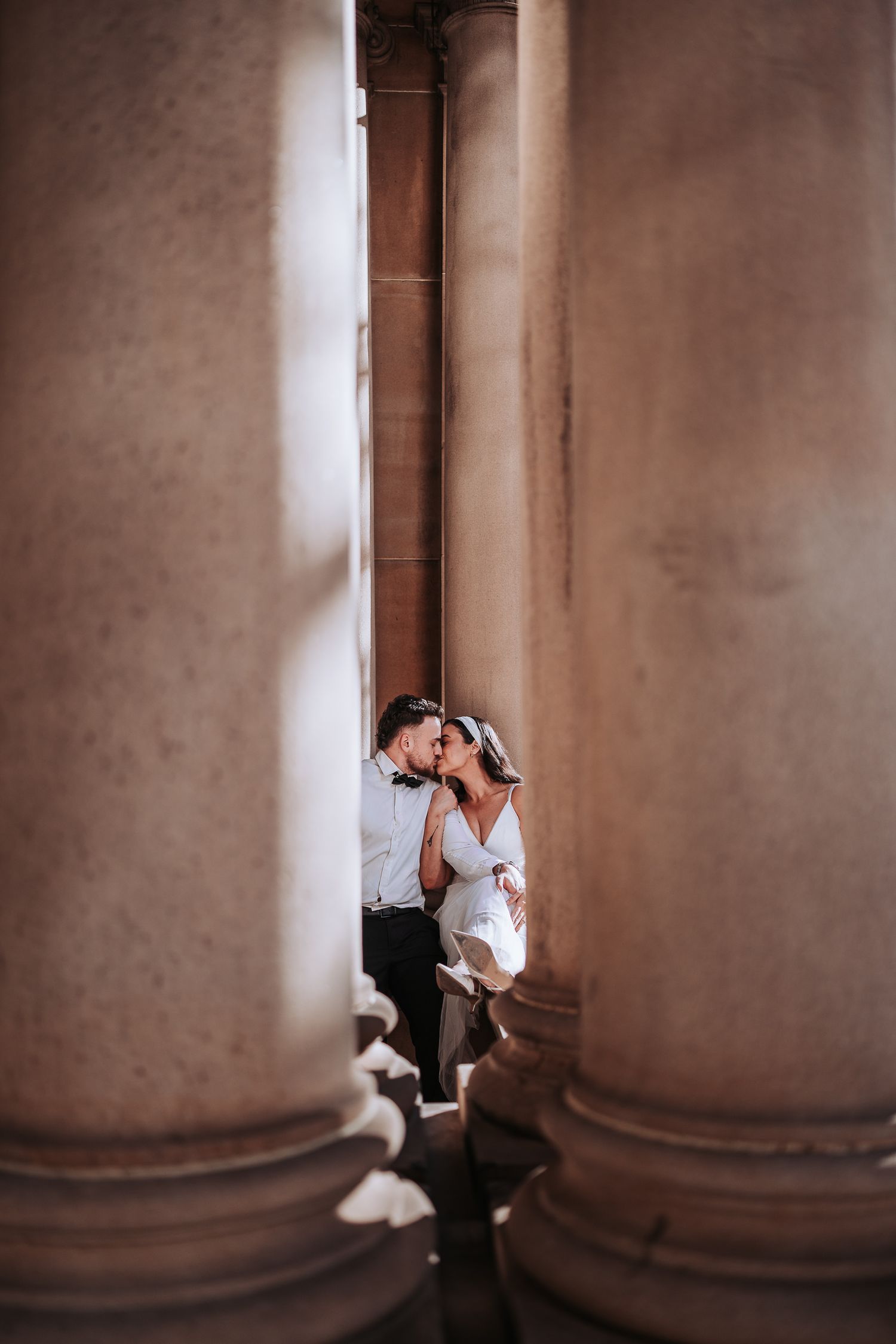 A series of four sepia-toned photographs showing a romantic moment between couple in an architectural setting with columns.