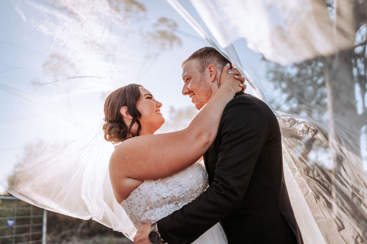 A romantic wedding moment captured with sunlight streaming through palm trees and a dreamy ethereal glow.
