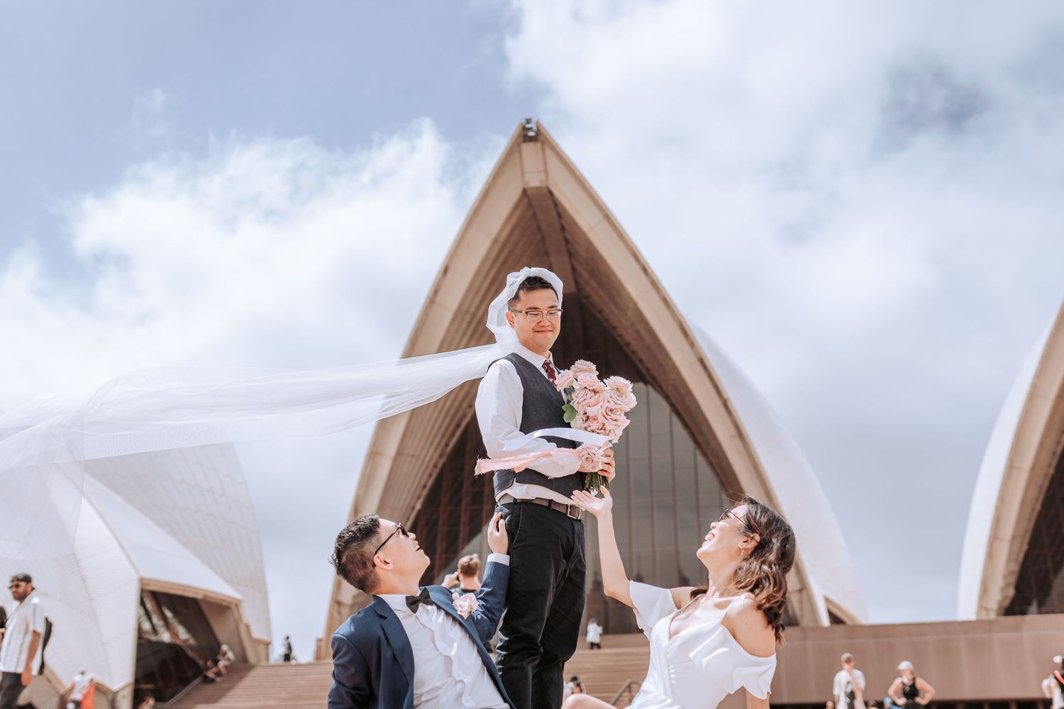 Wedding celebration with flowing veil in front of Sydney Opera House.