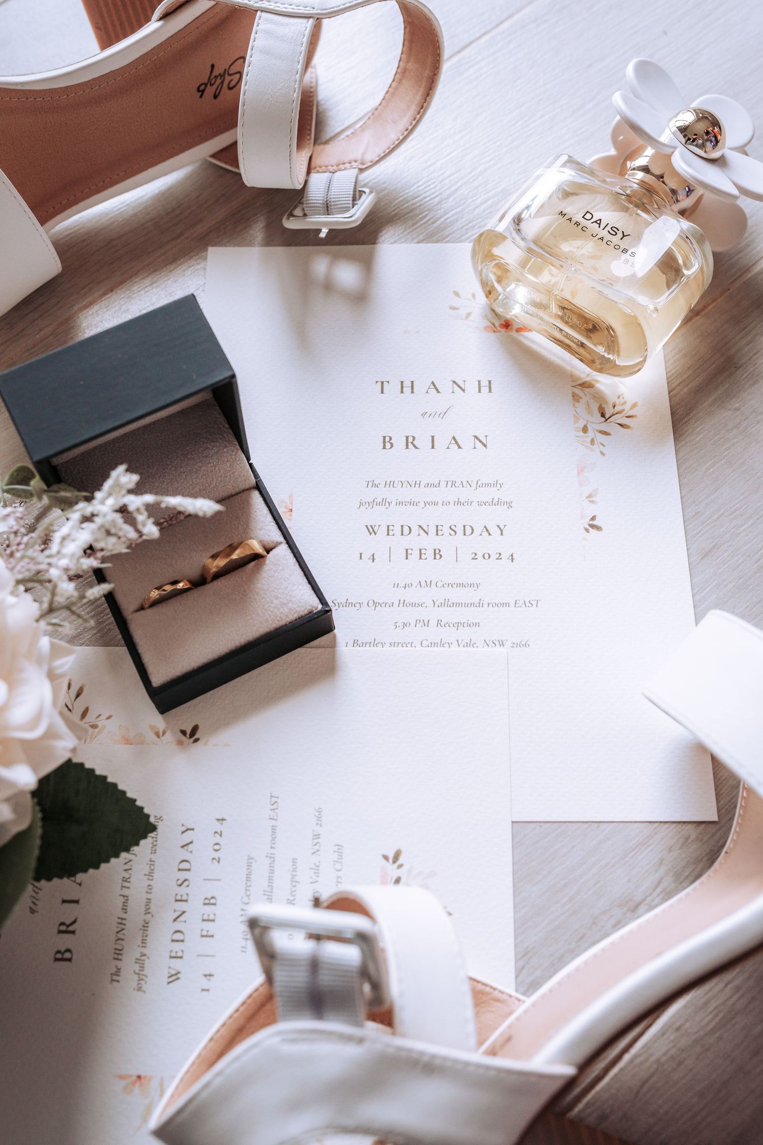 Elegant wedding invitations with romantic details and jewelry laid out on a white surface display minimalist design elements.