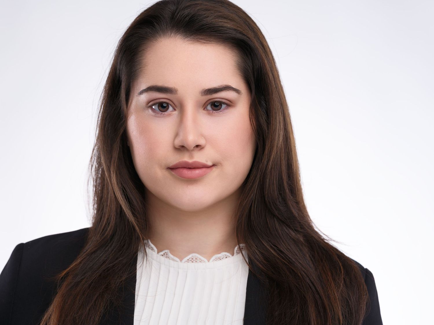 Professional business headshot with dark blazer and white lace-trimmed blouse against neutral background.