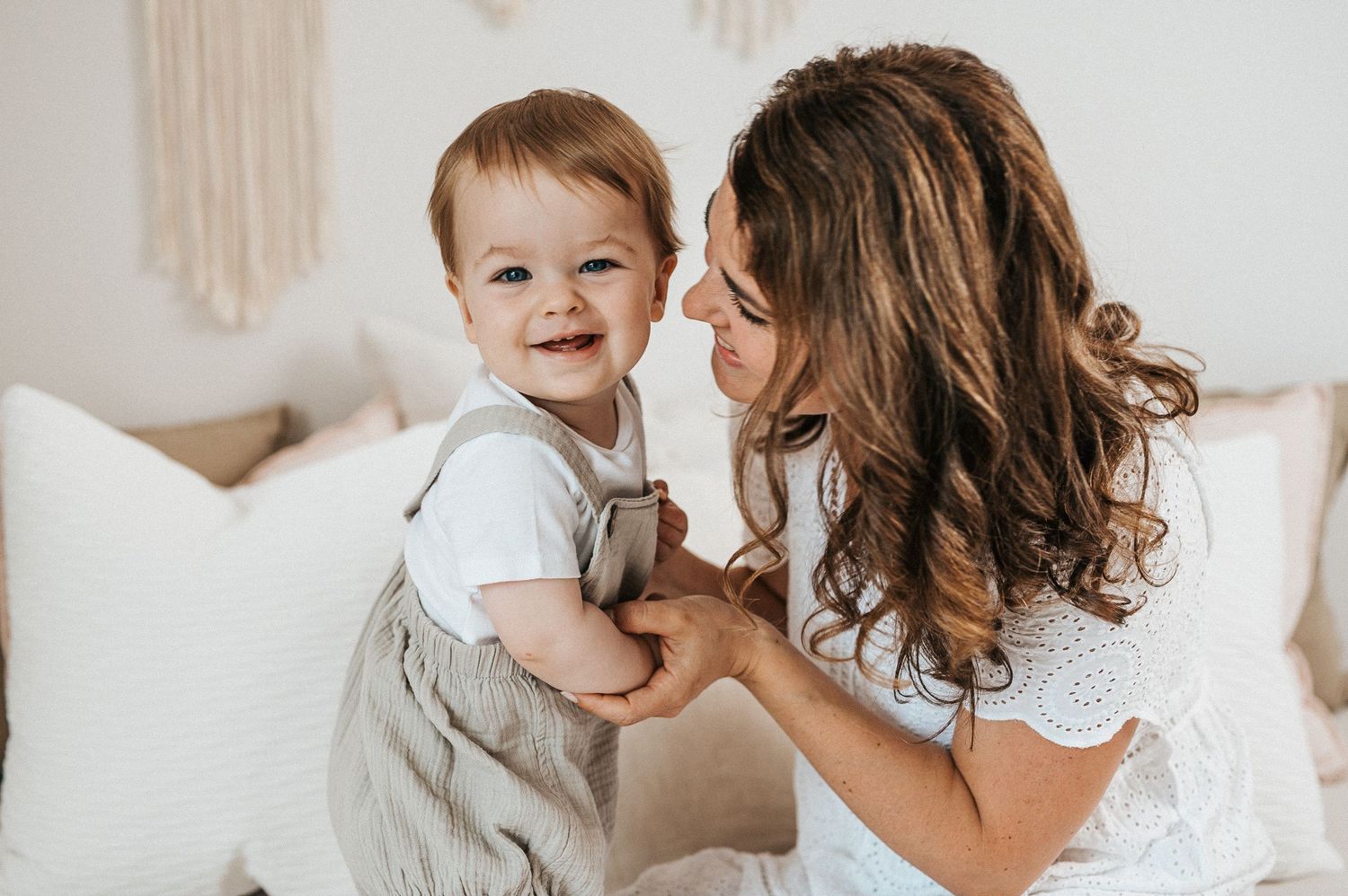 A tender moment captured between parent and child wearing matching light colors on a white couch.