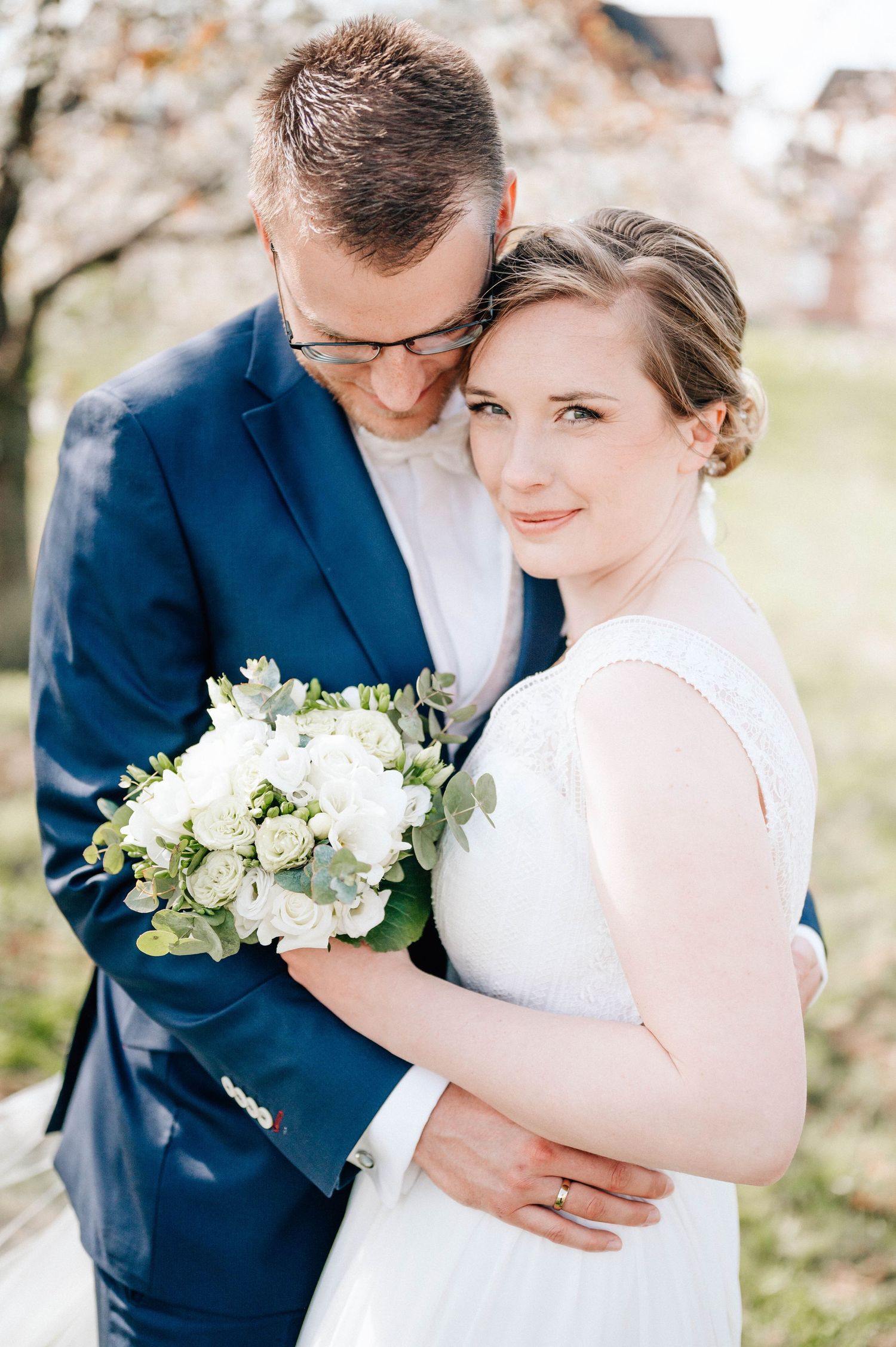 Intimate wedding portrait showing tender moment between newlyweds with white bouquet.