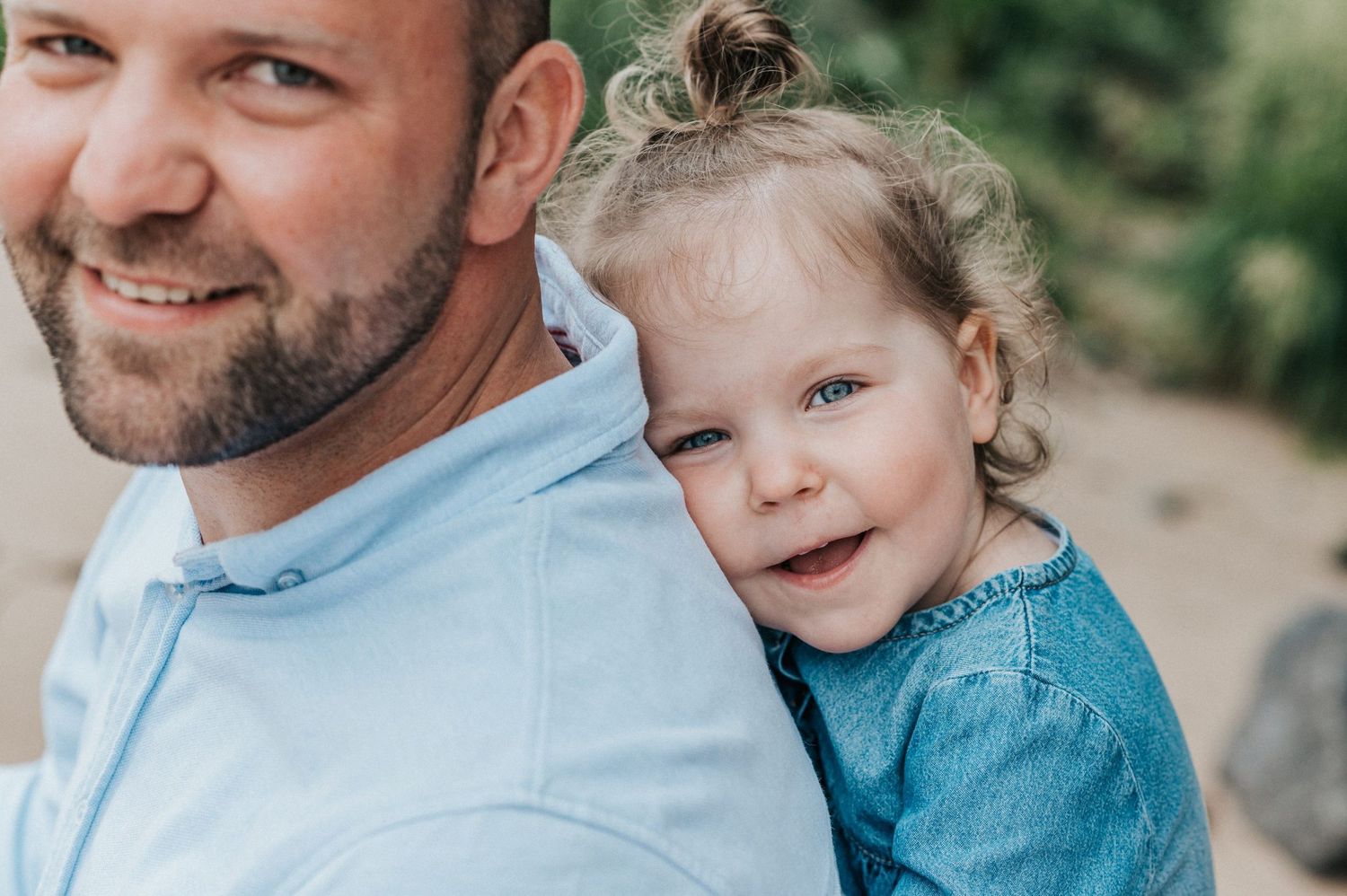 Close-up portrait of two people sharing a joyful moment against a natural backdrop.