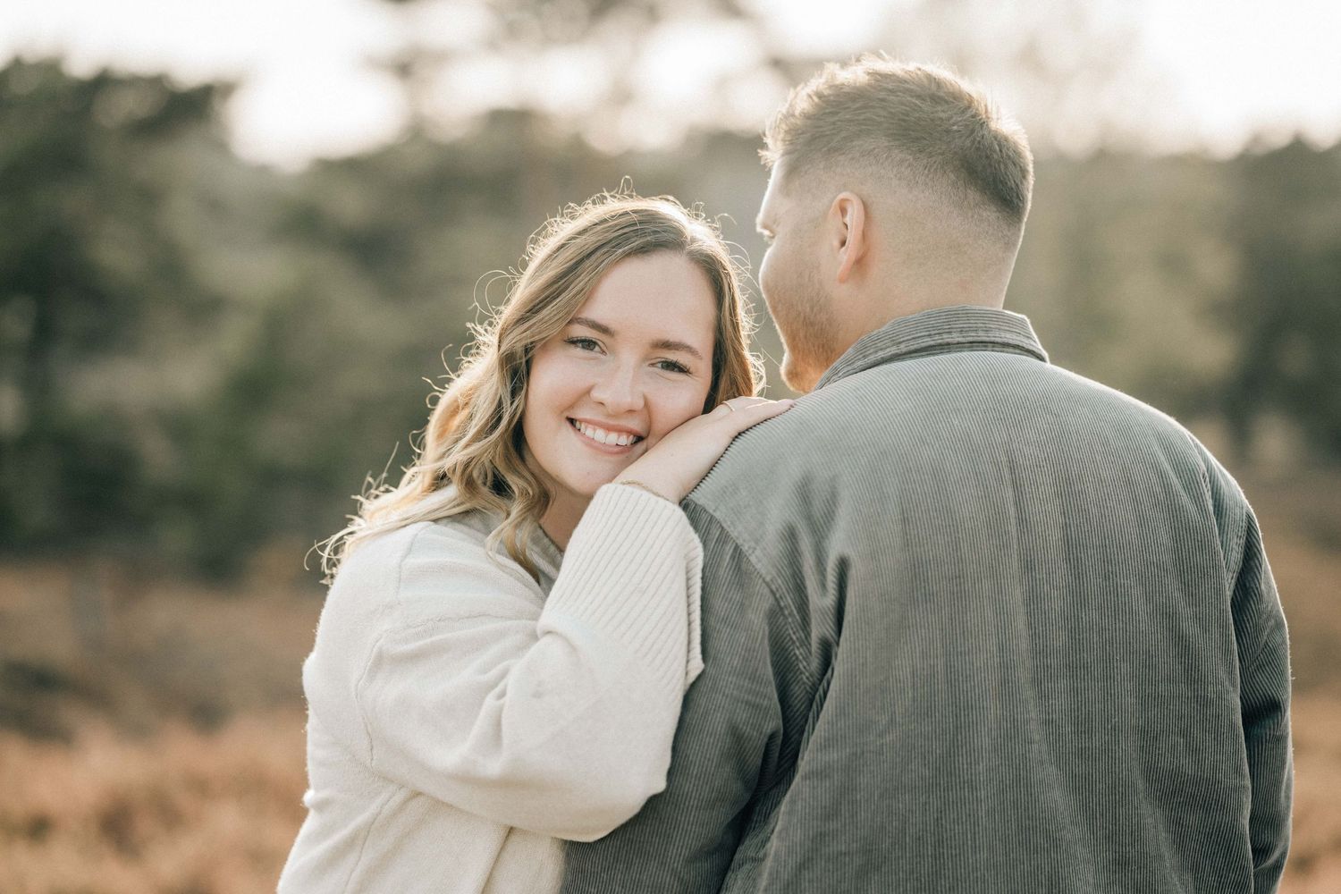A tender moment captured between a couple at sunset as they share a heartfelt laugh together outdoors.