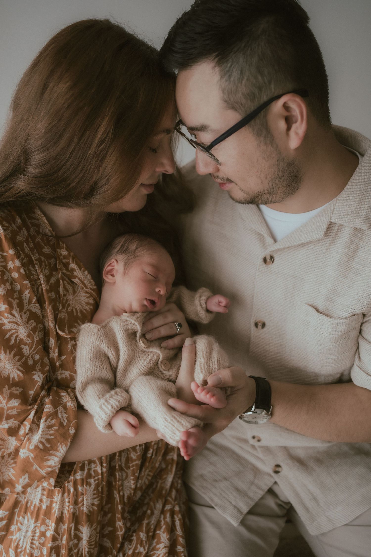 Intimate family moment with sleeping newborn baby in warm indoor lighting.